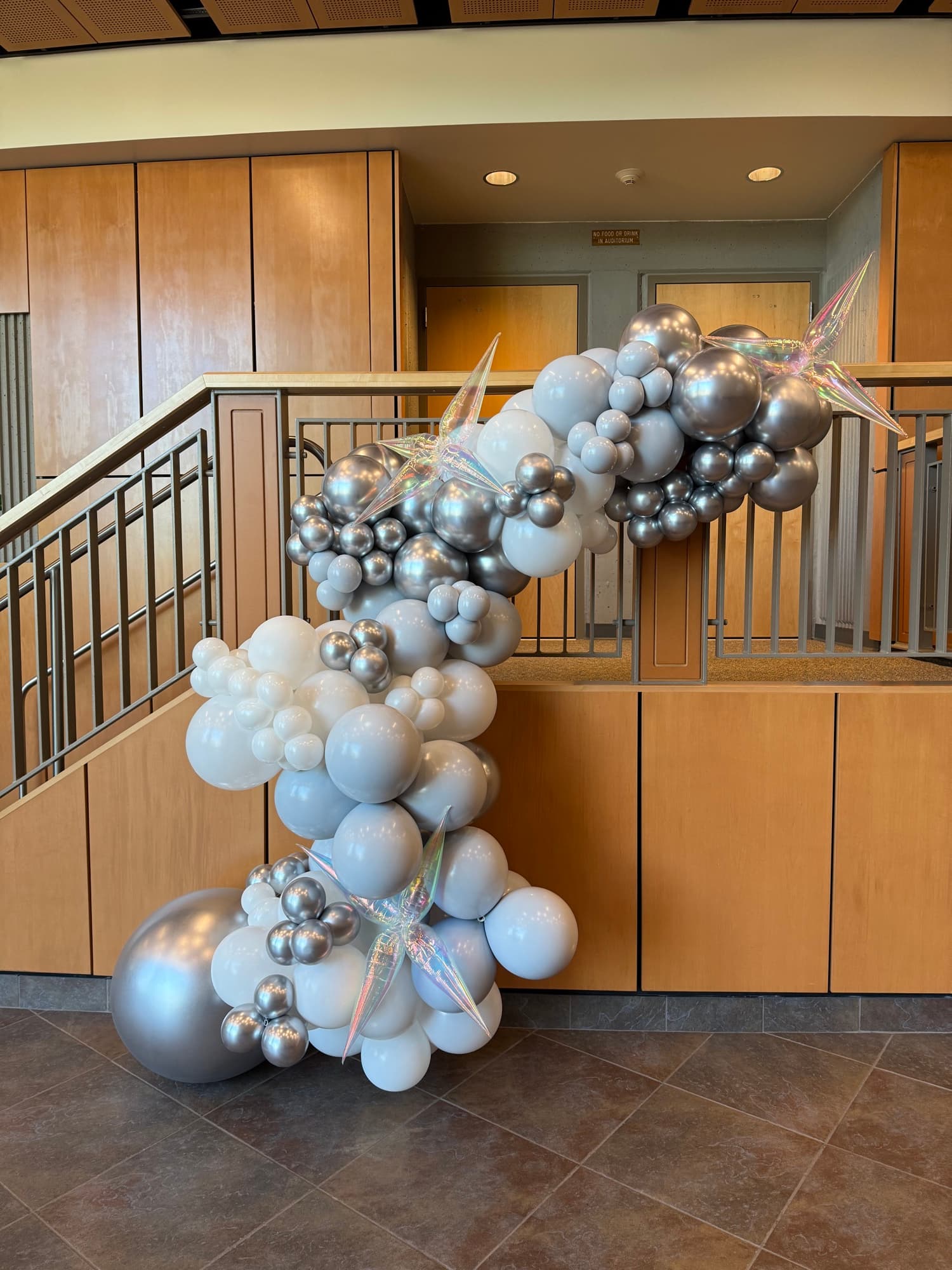 A sculptural silver and white balloon installation climbing an indoor event staircase.