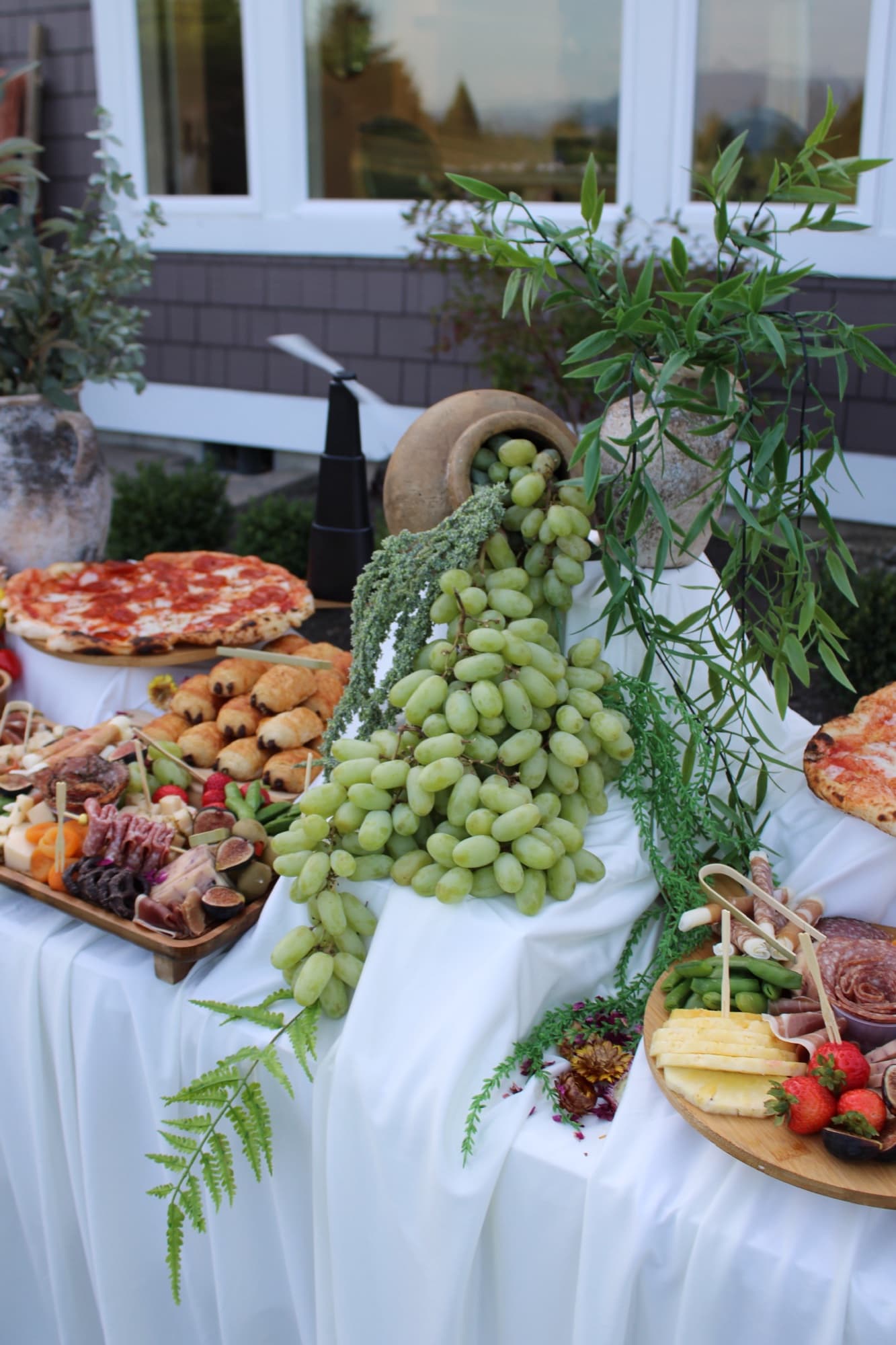 Forno Via grazing table with cascading grapes, charcuterie, greenery and artisan pizza.