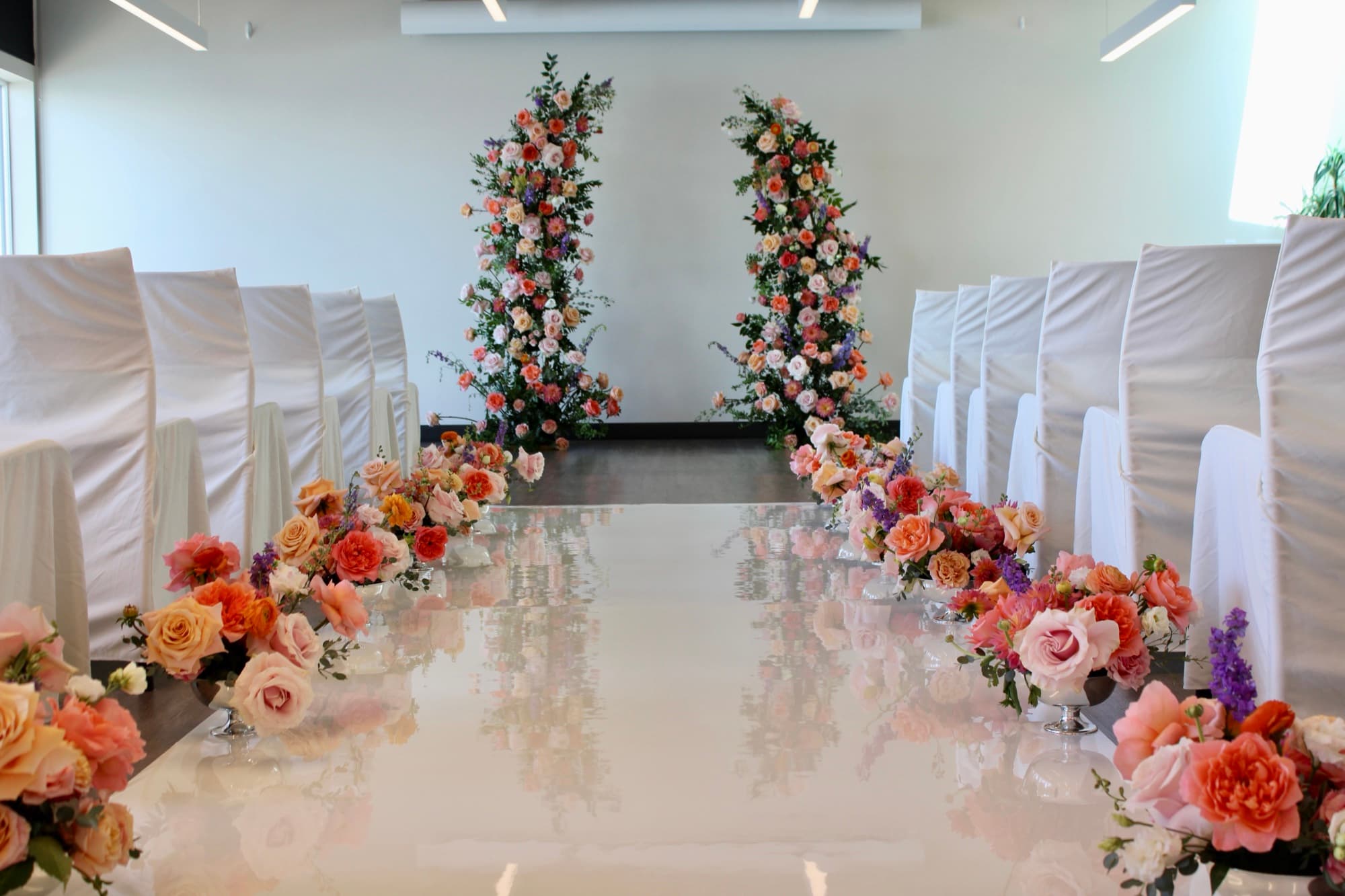 A wedding ceremony aisle with floral pedestals designed by Events by Juna.