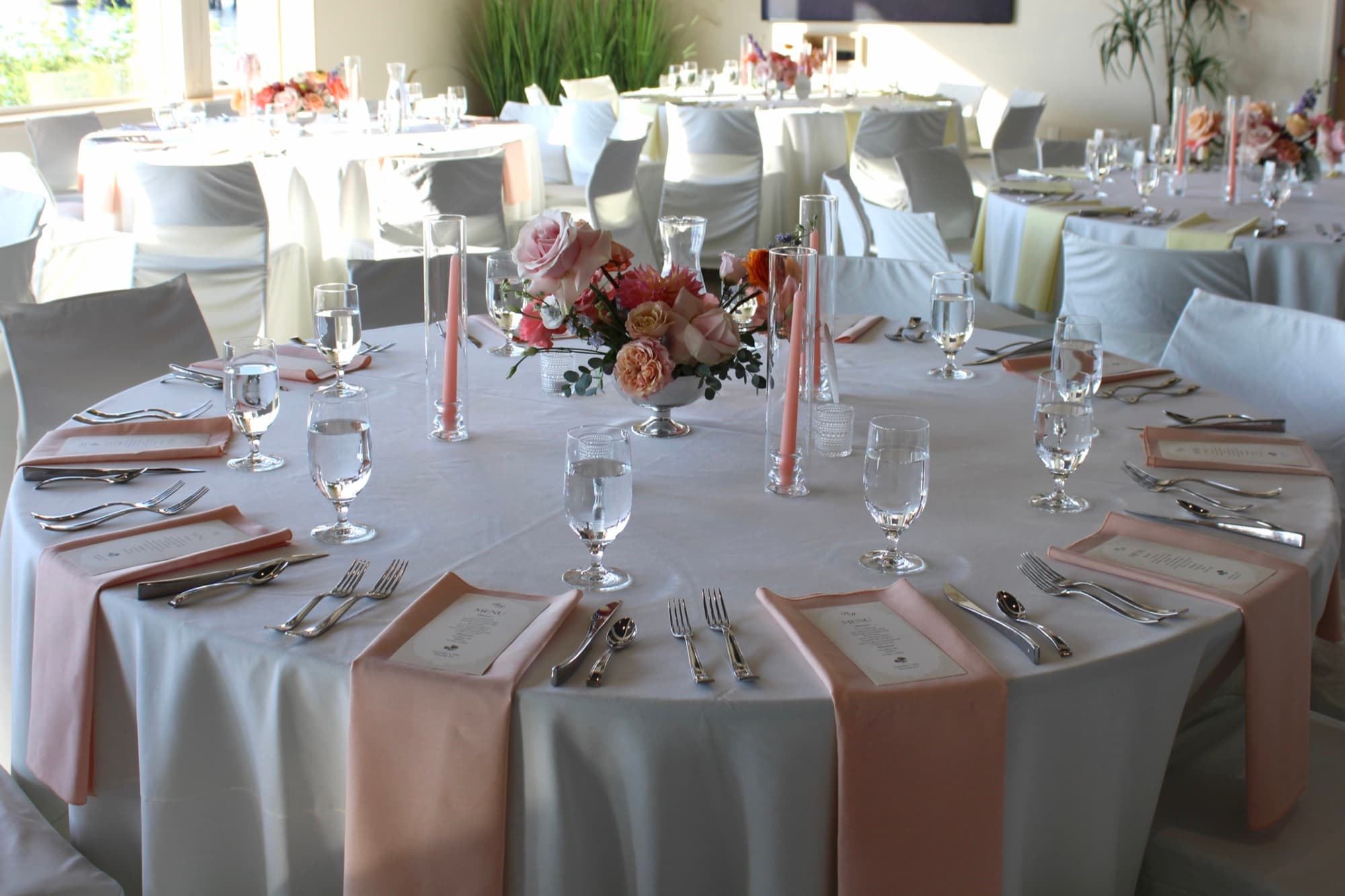 A finished blush wedding reception table with centerpiece and candlelight.