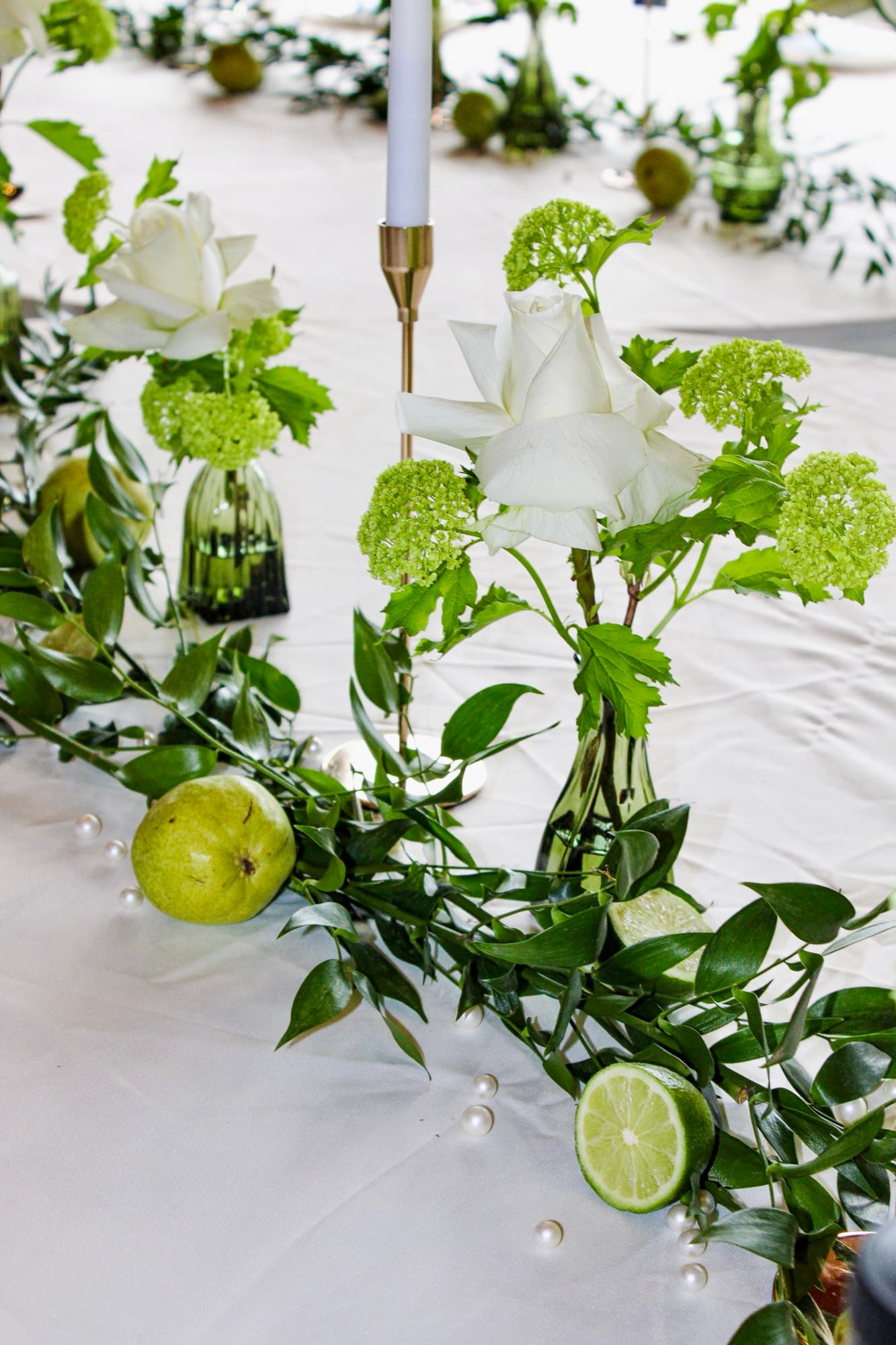 A green-and-citrus wedding tablescape detail with candles and glassware.