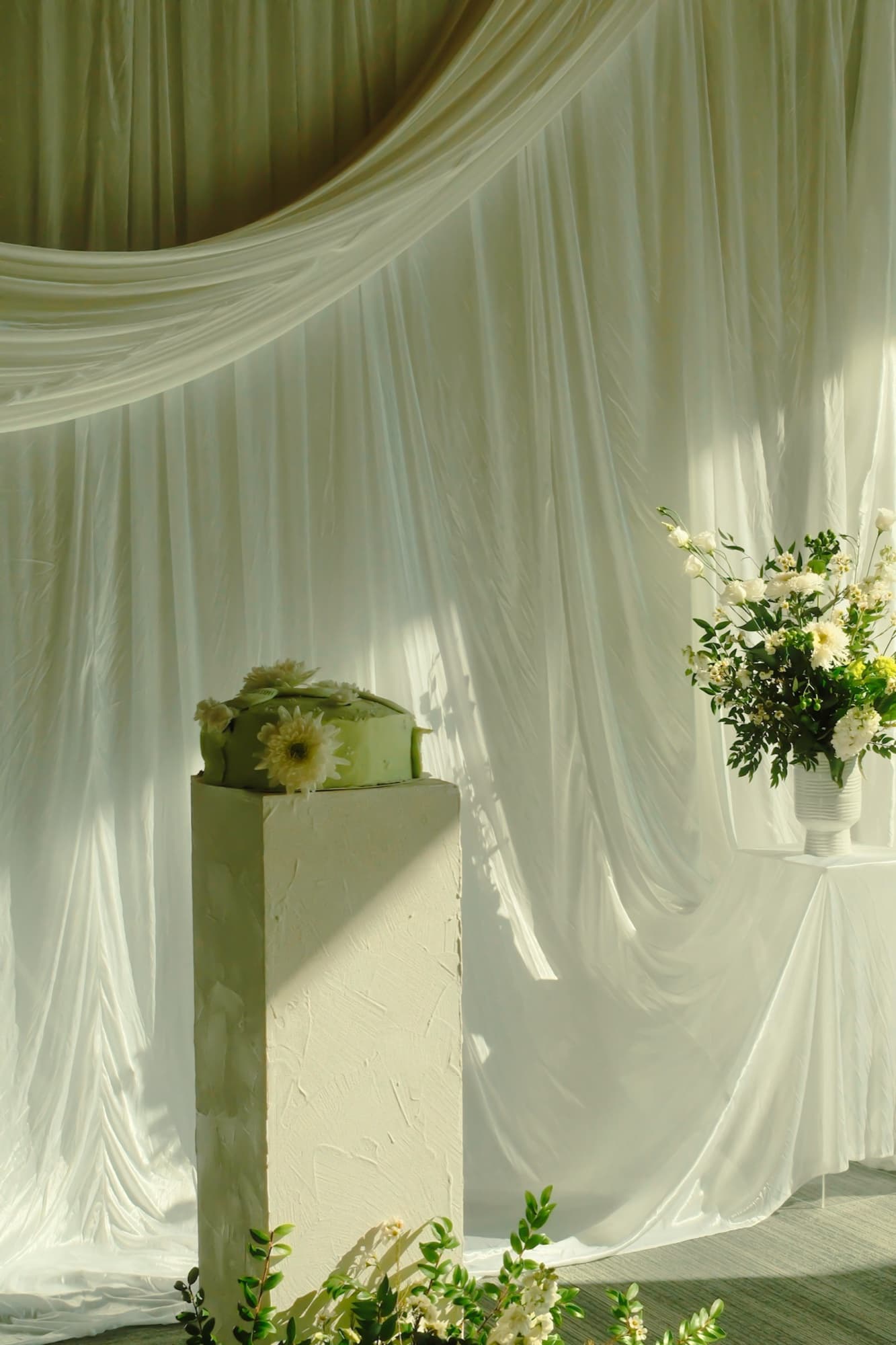 A white draped wedding ceremony with tall floral pedestals.